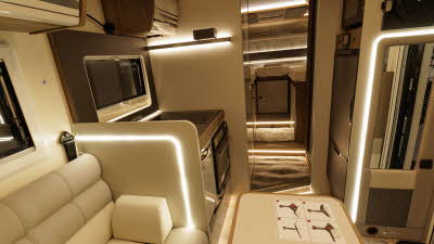 The Roller Team T-Line 750 has cream upholstery with matching furniture.  There's accent lighting.  The bedroom is at the rear and has a fixed bed.