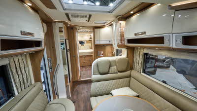 Carthago chic s-plus I 64 XL QB’s interior has beige leather upholstery.  The furniture is wooden with cream doors.  There is a large skylight.  There is a fixed bed to the rear.  