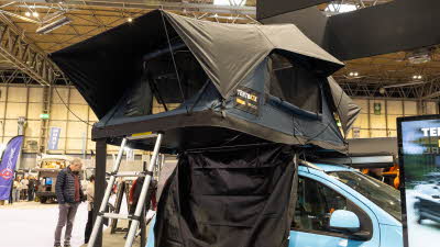 The TentBox Lite 2.0 has blue and black canvas.  It has a silver ladder to gain easy access.  It is shown on a blue car.