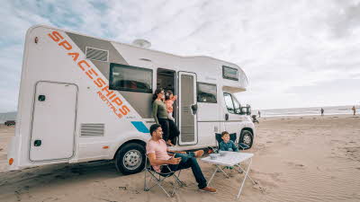 Family sitting outside their motorhome on a beach