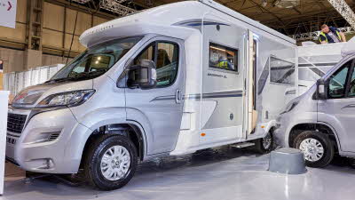 Auto-Sleeper Broadway EL exterior, the motorhome is silver and white, the rear habitation door is open showing into the interior, with a step to gain easy access. 