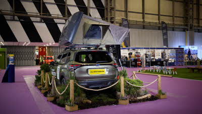 The ARB 4x4 Accessories Esperence is displayed on a green Subaru Forester.  It has khaki and cream canvas.  The window is open.  The hard top of the roof tent is pale grey.