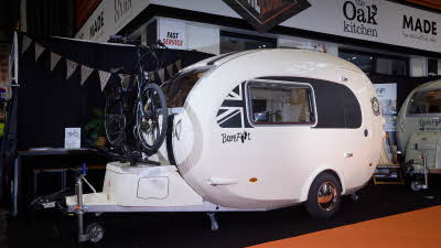 Barefoot Caravan Eclipse’s exterior is white with a black panel around the window with a part Union flag.  There is a mountain bike on a fitted bike rack over the locker at the front.