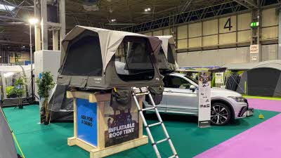 Dometic TRT 140 AIR roof tent is green with a khaki roof.  It is shown on a bespoke stand with a silver ladder to gain access.