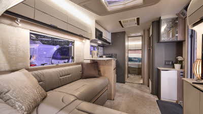 Swift Elegance Grande 860's interior has tan leather upholstery with pale cabinets.  The kitchen is placed in the centre with the washroom just beyond.  There is a rear bedroom and its door is open.