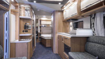 Knaus NorthStar 590 UE interior has wooden furniture with speckled white and dark grey upholstery.  The bedroom is at the rear.