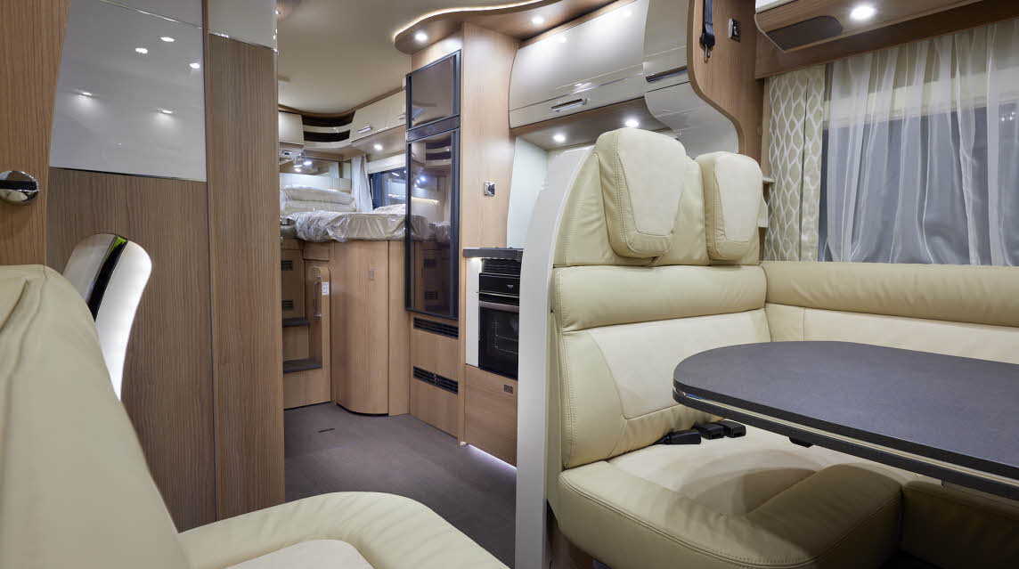 Carthago c-tourer T 148 LE H has cream leather upholstery, behind the rear travel seats Is the kitchen with a full oven and large fridge freezer.  At the rear of the vehicle is the fixed rear bed.