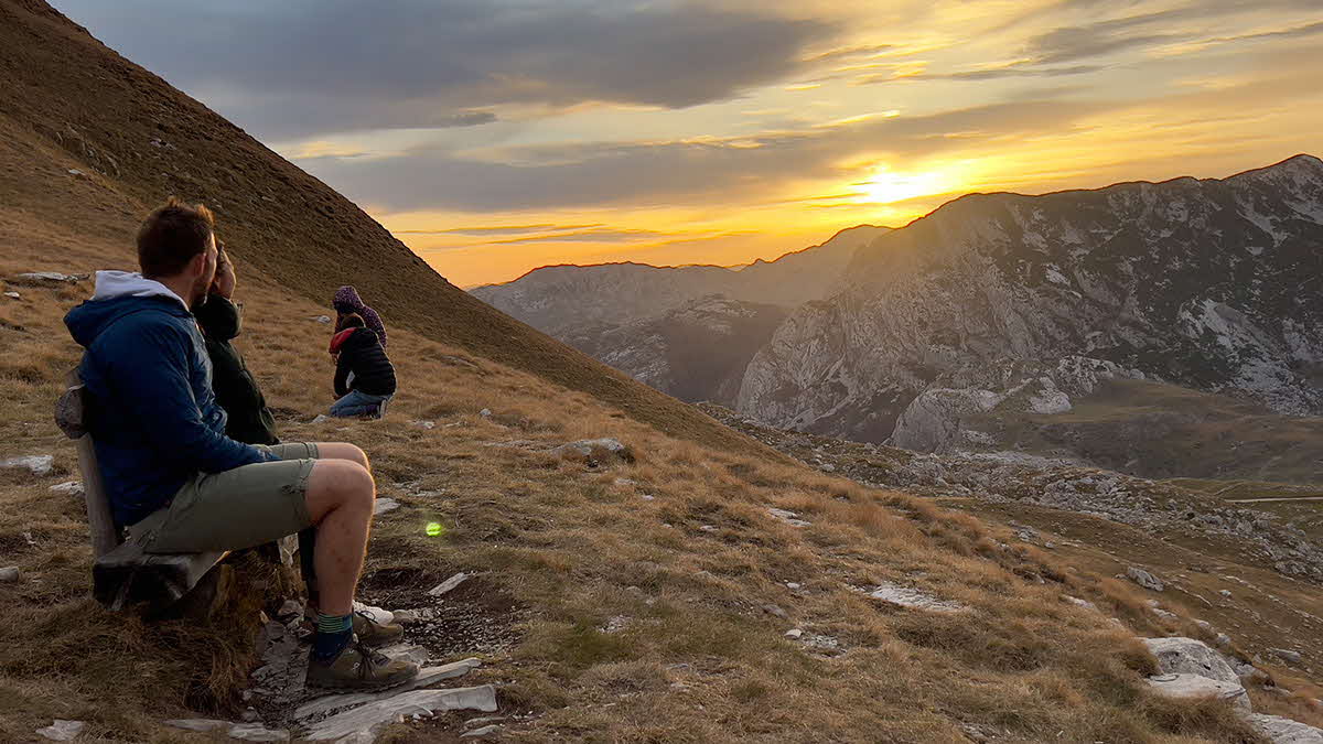 Marcus Leech and his family sitting on a bench enjoying the view of the mountains in Montenegro