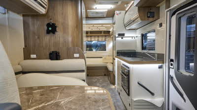 Roller Team T-Line 700’s interior has cream upholstery.  Its furniture is wooden.  At the rear there is a lounge.  There are two skylights and the kitchen is to the right.