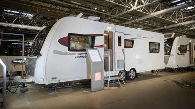 Elddis Avante 840 exterior is grey and white with black and red decals.  The door is open and there is a metal step to gain easy access to the interior.