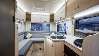 Auto-Trail F-Line F68 has two tone upholstery, with pale wooden furniture.  There is a round sink, hob with cover and oven in the kitchen.  The overhead lockers are pale wood and white.  