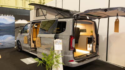 The Wildtracks Campervans Panoramic is light grey, its rear door and sliding door are open.  Its rising roof is fully erected.