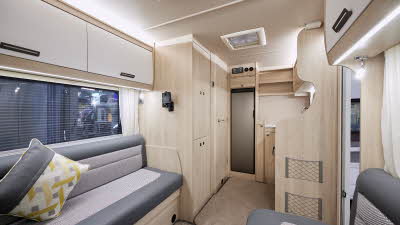Auto-Trail F-Line F62 has two tone upholstery, with pale wooden furniture.  There is an extractor fan in the kitchen ceiling.  The floor has removable beige carpet. 