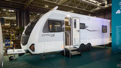 Swift Sprite Exclusive Quattro MB’s exterior is white with grey sides, it has a black and pale grey decal.  Its entrance door is open with two metal steps to gain easy access.  It has a roof light open.