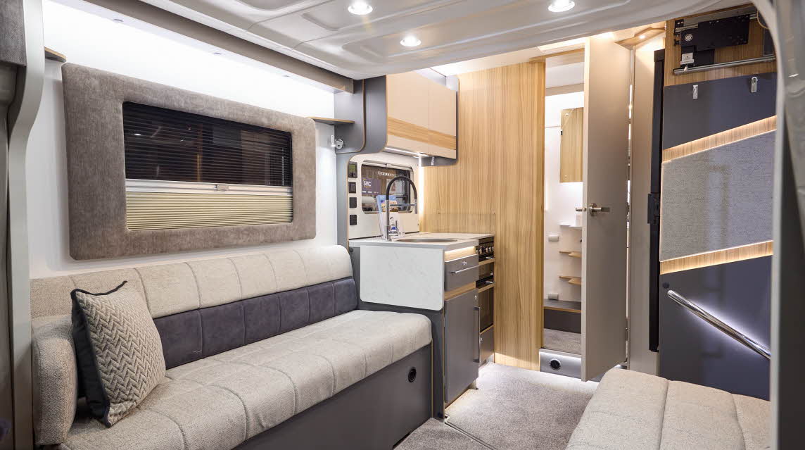 The Bailey Adamo 60-2 has grey carpets, with cream and pale wood cabinets.  The upholstery is cream and dark brown.  There is a step to the rear washroom.  There is a mid brown plinth around the lounge window.