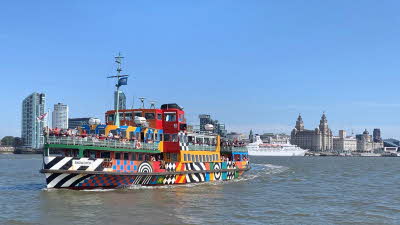 the brightly covered Mersey Ferry making the crossing on a sunny day