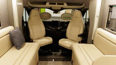 The Auto-Trail F-Line F67 has cream leather upholstery with pale wooden furniture and fittings.  The front two seats are swivelled to face into the van.  The floor has a grey carpet.