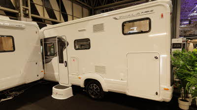 The Auto-Trail Imala 736 G has a white exterior decorated with grey decals, the cab is hidden.  There is an Auto-Trail step outside the habitation door.