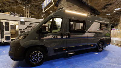 The Ace Motorhomes 1200 SLT is grey with a white decal, its rising roof is open.