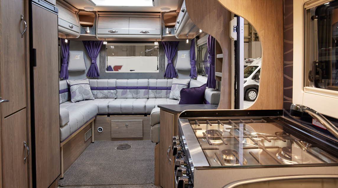 Wooden cabinets, dual fuel hob, white sofa with purple accent