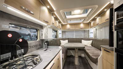 Frankia I 7400 PLUS Platin Pure Edition’s interior has wooden furniture with white surrounds.  There are two skylights.  The kitchen is central with the hob on the left and the fridge freezer on the right.  There is a u-shaped lounge to the rear.