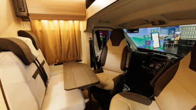 The Rimor Horus 54 has cream and dark brown upholstery, the front seats are swivelled into the dining area around the table. 