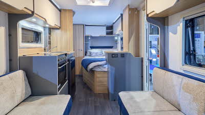 Bailey Discovery D4-4’s interior has beige upholstery with blue highlights.  There is a kitchen in the middle and there is a fixed French transverse bed towards the rear.