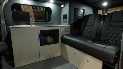 The Bespoke Leisure Bespoke Explore PHEV has black upholstery, its cabinets are white.  The lid to the sink is open.