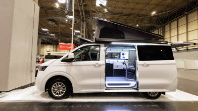 The Volksleisure Volkswagen Avoriaz T7 is white.  Its rising roof and sliding door are open.
