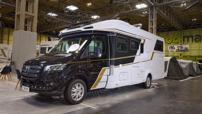The Eura Mobil Contura CT 766 EB has a black cab and white body with gold decals.  The two skylights are open.
