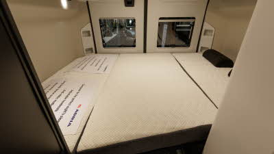 The Adria Twin Sports 600 SPB has cream walls either side of the fixed bed.