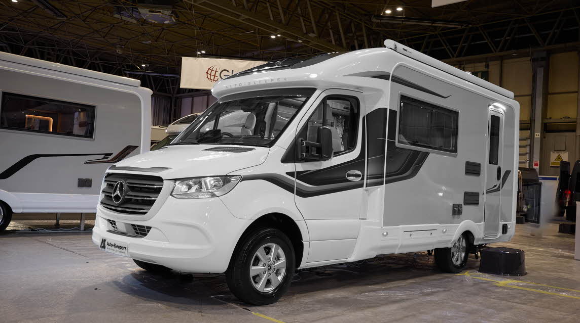 The Auto-Sleeper Bourton has a white exterior with a grey inset and black/grey decals.  There is a black step by the rear habitation door.