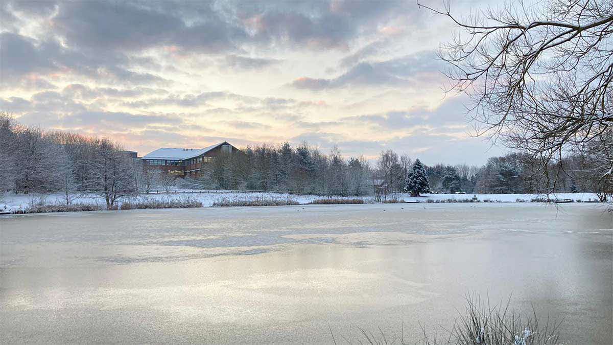 Photo of a frozen lake in winter, large cabin in the background