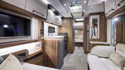 Interior of the Buccaneer Starliner Barracuda with cream sofas edged with suede effect material. The rear bedroom door is open revealing the fixed island transverse bed.  The large roof light will let natural light flood in.