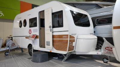 La Mancelle Fantaisy 440CL exterior is white with brown panels to the bottom of the front panel.  The door is open and there's a grey step to gain easy access to the interior.