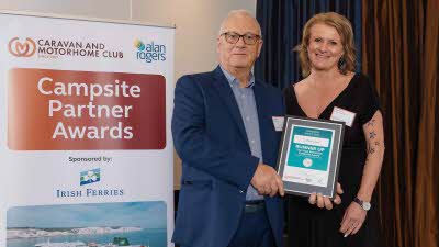 A Caravan and Motorhome Overseas Campsites Award Runner Up with the Chairman next to a sign showing Campsite Partner Awards, with Irish Ferries below it