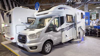 Bailey Adamo 69-4 exterior, the vehicle has a silver cab with the body being predominantly white, the habitation door is open showing into the interior, with a step to gain easy access.  There is an interactive tablet on a pedestal outside.  