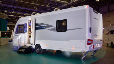 Swift Challenger Exclusive 560’s exterior is white with grey sides, it has a black and blue decal.  Its entrance door is open with a step to gain easy access.  Its two roof lights are open.