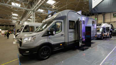 The Swift Trekker 584 is grey, its habitation door is open and there are two black steps to gain access.  There's an information board next to the steps.