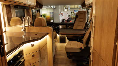 The MORELO PALACE 90M has a central kitchen with accent lighting.  There is a full oven to the right.  The front seats are turned so they form part of the lounge.  There is a large table.