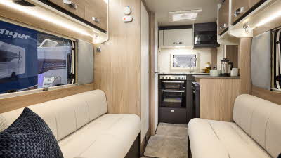 Interior of the Swift Challenger 390 with cream sofas, cosy cushions and beige carpets.  The kitchen is at the rear and there’s a skylight above it.