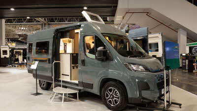 The Rimor Horus 54 is grey, its skylight and sliding door are open, there is a metal step in front of the interior to gain easy access.