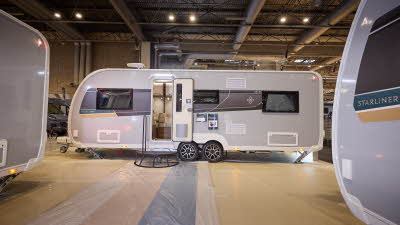 Buccaneer Starliner Aruba has a grey exterior with a black decal with a teal and yellow strip under the window.  The entrance door is open and there is a black metal step to gain easy access to the interior.