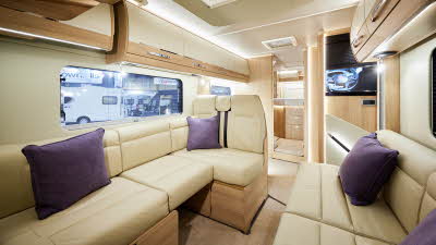 Auto-Trail Grande Frontier GF-88 has cream leather upholstery, with wooden furniture.  The floor has beige carpet.  The overhead lockers are cream with wooden surrounds.  There are four purple cushions