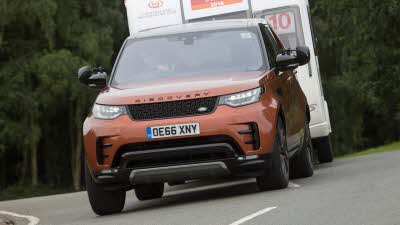 Rust coloured Land Rover Discovery towing a caravan