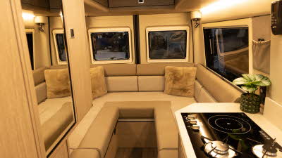 The RP Motorhomes Rebel U has caramel and cream u shaped sofas with two matching cushions in the corners.  The cabinets are made of wood and there is a dual fuel hob in the right corner with a pot plant.
