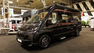 The Auto-Trail V-Line 610 Sport is black with two red striped decals its sliding door is closed.