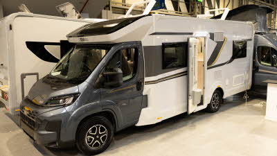 The Elddis Avalon 255 with XT Pack has a grey cab and a white coachbuilt body.  It has grey and yellow decals.  Its two skylights and habitation door is open.