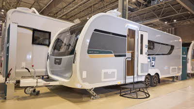 Buccaneer Skylinder Bermuda has a grey exterior with a black decal with a teal and yellow strip under the window.  The entrance door is open and there is a black metal step to gain easy access to the interior.