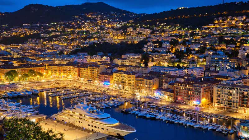 View of Old Port of Nice with luxury yacht boats from Castle Hill, France, Villefranche-sur-Mer, Nice, Cote d'Azur, French Riviera in the evening blue hour twilight illuminated